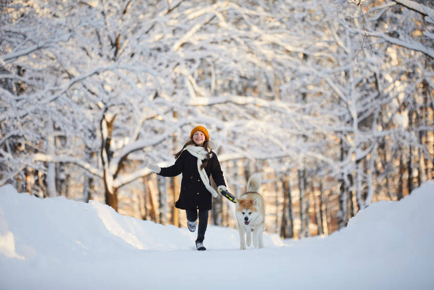 Girl running with dog in winter woods